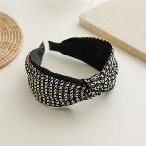 Detailed close-up of a wide knotted houndstooth headband with elegant black and white texture