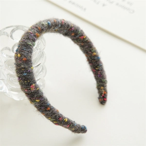 Détail d'un serre-tête en tricot gris foncé avec des points colorés pour l'hiver