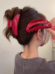 Vue détaillée de pinces à cheveux en acétate bordeaux avec lettrage doré