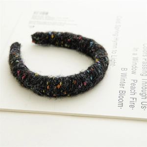 Détail du serre-tête en maille noire épaisse avec accents de fils de laine colorés