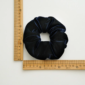Flat lay of a large navy blue velvet scrunchie with measuring rulers showing size details