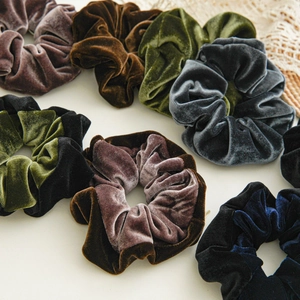 Detail of elegant velvet hair scrunchies in vintage brown, green, grey, and black tones