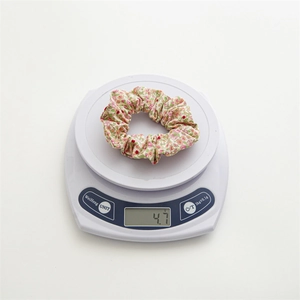 Chouchou en coton à motif floral pesant 4,7g sur une balance montrant sa légèreté