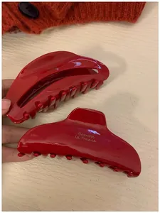 Détail de pinces à cheveux en acétate rouge brillant avec marquage doré et fini poli