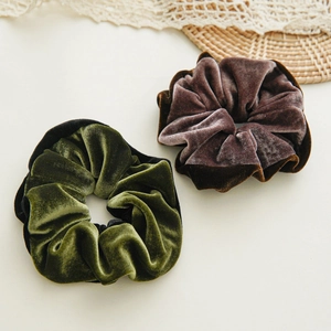 Elegant velvet scrunchies in dark green and plum purple colors on a rustic background