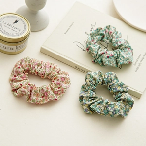 Gros plan sur trois chouchous en coton aux motifs floraux roses, bleus et verts