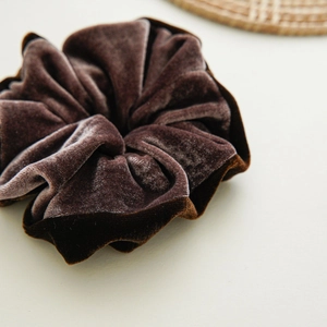Detail shot of the plush texture and silky sheen of the dark brown velvet scrunchie