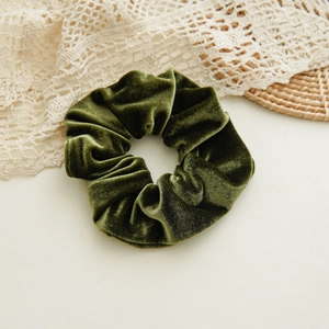Detail of dark green velvet scrunchie showing plush texture and soft fabric sheen