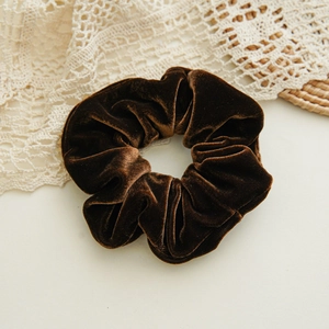 Close-up of elegant brown velvet scrunchie with soft pleats and glossy fabric texture
