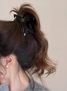 Gros plan d'une pince à cheveux minimaliste noire en forme d'étoile sur cheveux