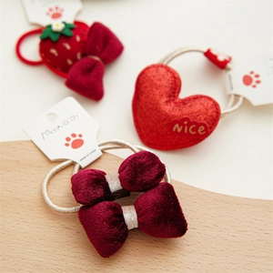 Detalle de lazos de terciopelo rojo y gomas de pelo con corazón de purpurina en madera