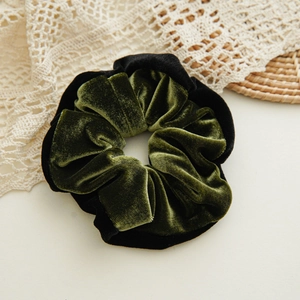 Detailed macro view of high-quality dark green velvet scrunchie with black trim