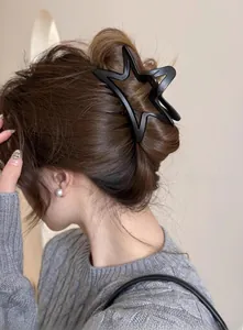 Vue détaillée d'une pince à cheveux noire mate en forme d'étoile sur les cheveux d'une femme