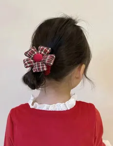 Detalle de una niña con coletero de flores a cuadros rojos y verdes y bola de terciopelo