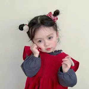 Detalle de niña con lazo floral rojo y coletero de pompón suave para el cabello