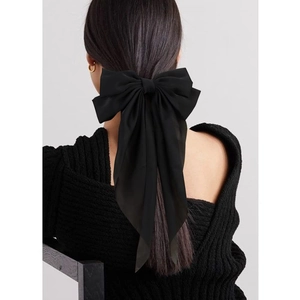 Dettaglio di un grande fiocco per capelli in raso nero con nastri lunghi sulla coda
