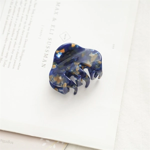 Detail einer 5,5 cm Acetat-Haarklammer mit dunkelblauem Schildpattmuster auf einem Buch
