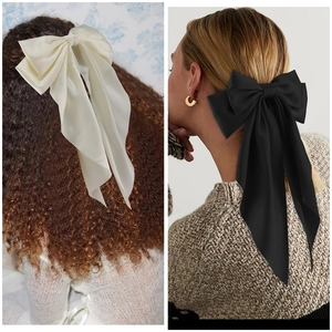 Dettaglio di eleganti fermagli per capelli in raso con lunghi nastri nei colori crema e nero