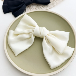 Dettaglio del fermaglio per capelli in raso bianco crema con elegante fiocco