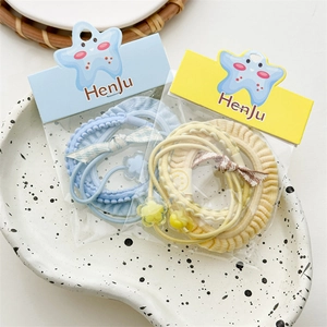 Detail of candy-colored elastic hair ties with floral charms and plaid bows in a tray