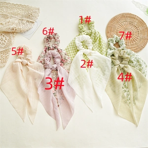 Flat lay of seven colorful floral chiffon scrunchies with long ribbons for ponytails