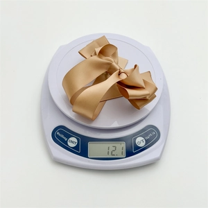 Detailed view of lightweight 12.1g champagne satin bow hair clip on a digital scale