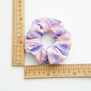 Detailed view of tie-dye fabric scrunchie with 10cm diameter measurement on white background
