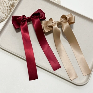 Close-up of elegant burgundy and champagne triple bow hair clips with long satin ribbons