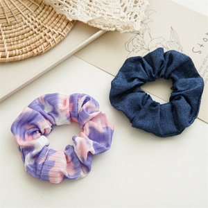 Close-up of tie-dye marble texture and blue denim fabric scrunchies on a soft background