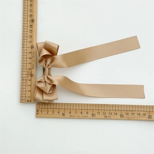 Detailed view of champagne satin bow hair clip with long ribbons and size measurement