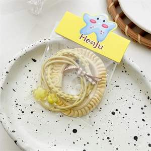 Close-up of three-piece yellow hair ties set with star pendant on a ceramic tray