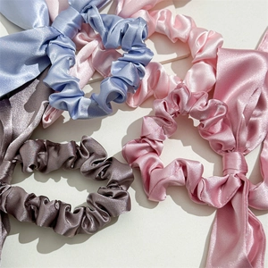 Detail showing various colors of satin bow scrunchies with elegant silky texture