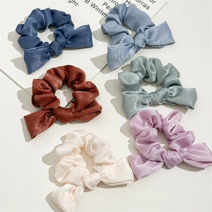 Detailed view of six assorted satin knotted hair scrunchies in various pastel colors