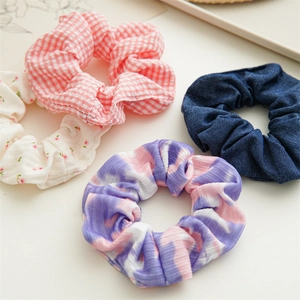 Floral and plaid fabric scrunchies in pink, blue, and purple set on cream background