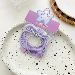 Detailed view of purple elastic hair ties set with plaid bow and heart charms on a plate