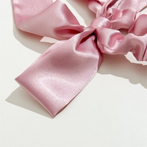 Close-up of soft pink satin bow hair tie with smooth silk texture and elegant drape