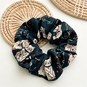 Vue détaillée du chouchou en tissu bleu marine avec motif de chat porte-bonheur blanc