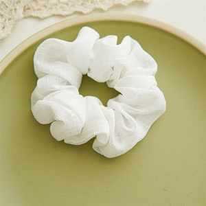 Dettaglio di scrunchie bianco a quadri con paillettes su un piatto di ceramica