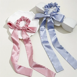 Detail of pink and blue satin bow scrunchies with long streamers on a white tray