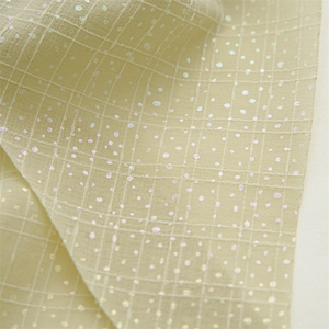 Macro view of light beige checkered fabric with iridescent laser dots and fine texture