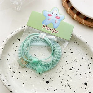 Detail of mint green hair tie set with heart and star charms on decorative paper card