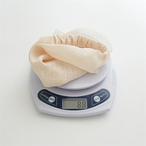 Detail shot of beige elastic hair bandana with silver dots on a digital scale