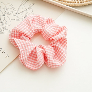 Detailed close-up of pink and white checkered fabric scrunchie with soft ruffled texture