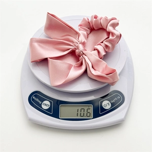 Pink satin bow hair scrunchie with high elasticity weighing 10.6g on a digital scale