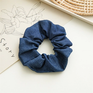 Detailed view of navy blue denim fabric scrunchie with vintage texture on white desk
