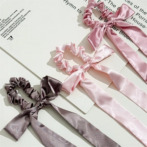 Three elegant satin bow scrunchies in pink and purple colors with long flowing streamers