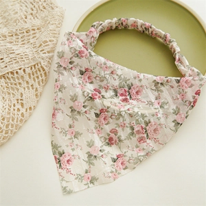 Detail view of floral headscarf with pink rose patterns and elastic band on textured fabric
