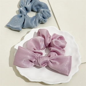 Detailed view of soft satin bow scrunchies in purple and light blue with pearly sheen