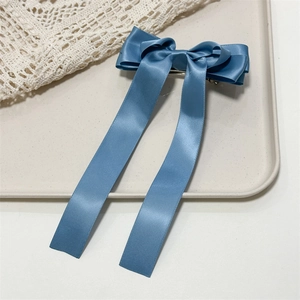Close-up of grey-blue satin bow hair clip with ribbons and metal spring fastener