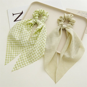 Detail showing two floral hair scrunchies with long streamers on a cream tray